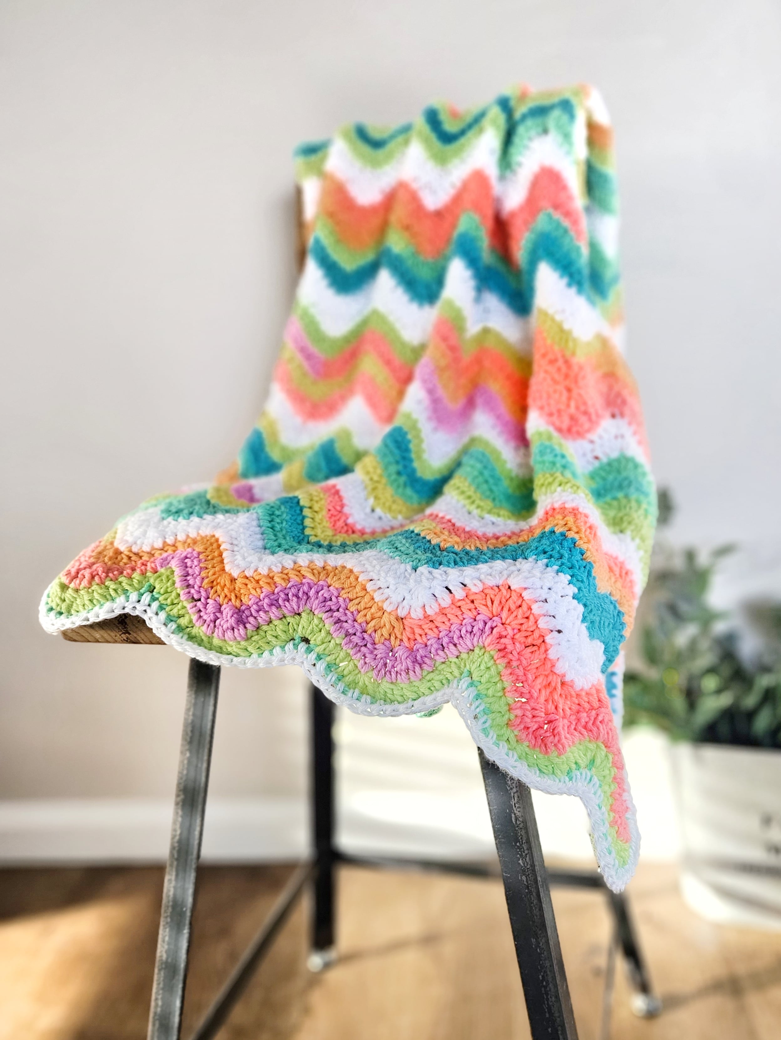 rainbow crochet blanket on a chair
